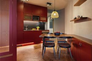 柏林Downtown Apartments Mitte-Wedding的厨房配有红色橱柜和木桌及椅子