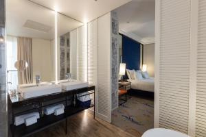 马德里Pestana Plaza Mayor Madrid的浴室设有2个水槽、1张床和1面镜子