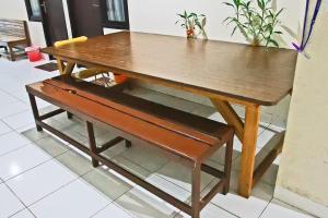 巴厘巴板RedDoorz Plus at Pelita Guest House Balikpapan的旁边一张木桌,旁边设有长凳