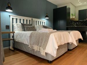 东伦敦Coral Wood Self Catering Suites and B&B的卧室配有一张带白色床单和枕头的大床。