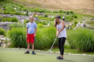 蓝山Blue Mountain Resort Village Suites的高尔夫球上打高尔夫的女人和孩子