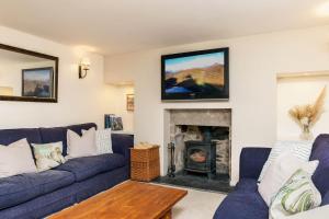 巴拉特Riverside Cottage with wood fired hot tub in Cairngorms的客厅设有蓝色的沙发和壁炉