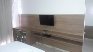 若昂佩索阿Mar do Cabo Branco Residence的卧室配有一张桌子,墙上配有电视