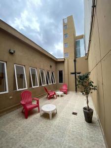 萨尔塔Eco Plaza Hotel的大楼内的阳台配有红色椅子和桌子