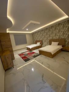 Al Humaizahشاليهات لودج的一间卧室设有两张床,墙上配有电视。