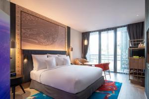 芭东海滩Hotel Indigo Phuket Patong, an IHG Hotel的卧室配有一张白色的大床和一张桌子
