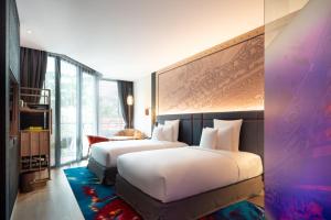 芭东海滩Hotel Indigo Phuket Patong, an IHG Hotel的酒店客房设有两张床和大窗户。