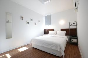 釜山Ekonomy Haeundae Hostel的白色卧室配有一张带白色床单的大床