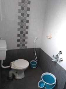 贝尔高姆RAJE SAMBHAJI GUEST HOUSE的浴室设有卫生间和2个桶,位于地板上