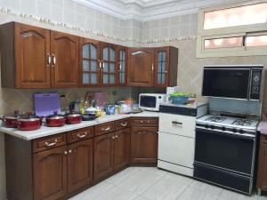 十月六日城Elite Homes 3BR Garden Apartment Families Only的厨房配有木制橱柜和炉灶烤箱。