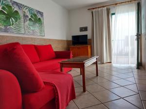 卡门港阿库阿里奥索尔公寓的客厅配有红色的沙发和桌子