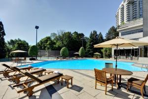 多伦多多伦多泛太平洋酒店的一座带桌子和遮阳伞的游泳池位于一座建筑旁边