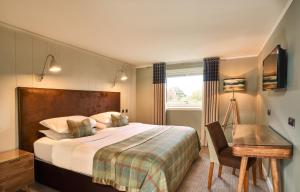 克雷格纽尔马尔岛Spa酒店 的一间卧室配有一张床、一张书桌和一个窗户。