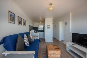 布鲁堡史特兰Blouberg Beachfront Apartment - Loadshedding free的客厅配有蓝色的沙发和电视