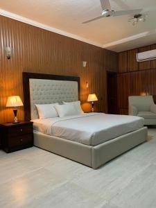 伊斯兰堡Royal Motel Executive的一间卧室配有一张大床、两盏灯和一把椅子