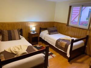 纳塔列斯港Hostal America en Puerto Natales的一间卧室设有两张床和窗户。