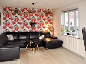 曲博伦Holiday home Thyborøn IV的客厅配有黑色真皮沙发和花卉墙
