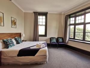 悉尼悉尼克雷西酒店的一间卧室配有一张大床和两把椅子
