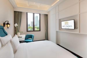 雅加达Hotel Des Indes Menteng的配有一张床、一张书桌和一扇窗户的酒店客房
