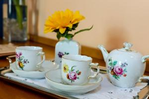 瓦雷泽卡格罗纳别墅酒店的一个带三个茶杯的托盘和一个黄色花瓶