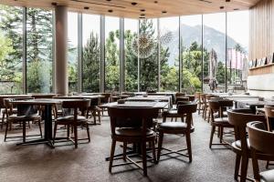 博尔米奥Eden Hotel的餐厅设有桌椅和大窗户。