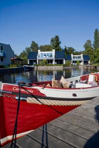 洛斯德雷赫特阿姆斯特丹/鲁斯德雷奇璃园范登布如科村度假屋的一艘红白船停靠在码头