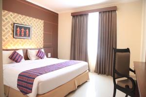 马卡萨Aerotel Smile Losari的配有一张床、一张书桌和一扇窗户的酒店客房
