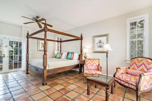 西棕榈滩Grandview Gardens的一间卧室配有一张天蓬床和一把椅子
