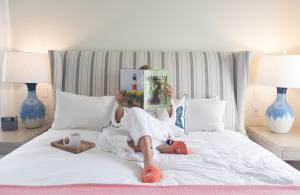 楠塔基特The Nantucket Hotel & Resort的躺在床上读书的女人