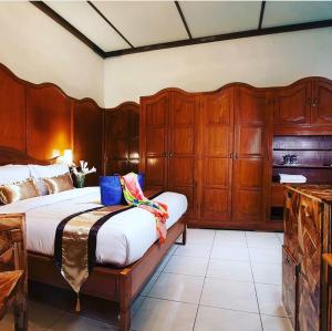 日惹雨树精品别墅及画廊旅馆的一间卧室配有一张大床和木制橱柜。