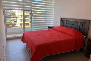 维纳德马Arriendo departamento excelente ubicación por día的一间卧室设有红色的床和大窗户