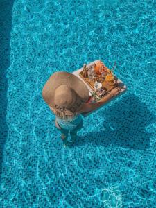 斯普利特Agava Lux Rooms&Pool的坐在游泳池里的草帽里的人