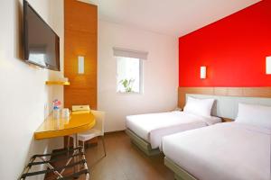 库塔日落大道巴厘岛爱玛黎丝酒店的酒店客房设有两张床、一张桌子和一台电视。