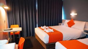 霍巴特海滨洛奇汽车旅馆的酒店客房带两张床和一张桌子以及椅子。
