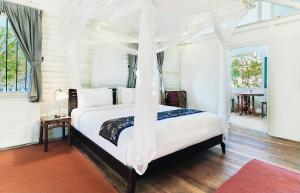 珍南海滩Temple Tree Resort的一间卧室配有一张带天蓬的白色床