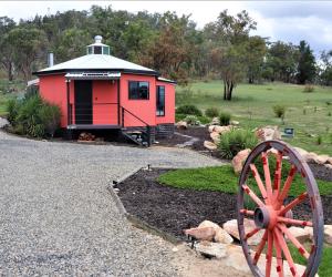 BallandeanA Stanthorpe Getaway的一座红色的建筑,在院子里有轮子