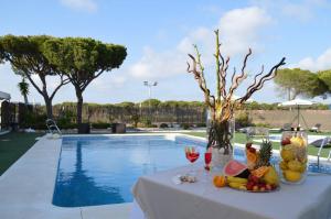 马札冈阿尔拜达自然酒店的游泳池旁的一张桌子,上面摆放着水果和酒杯
