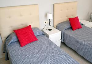 阿尔考斯布里吉恩广场罗曼娜公园公寓式酒店的卧室内的两张床和红色枕头