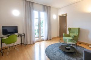 伊伦乌尔达尼比亚酒店的客厅配有两把绿色椅子和电视