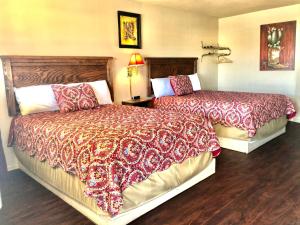 LevellandBest Inn Texas的酒店客房,配有两张带红色毯子的床
