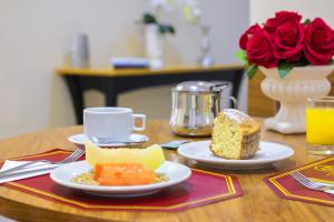 索罗卡巴Hotel Dan Inn Sorocaba的一张桌子,上面放着两盘食物和一块蛋糕