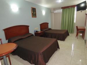 比亚埃尔莫萨Hotel San Juan Centro的酒店客房设有两张床和一张桌子。