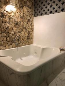 巴利亚多利德Hotel Boutique Bugambilias的浴室配有白色浴缸及石墙