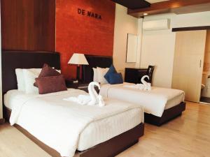 清迈Hotel De Nara-SHA Extra Plus的两间天鹅坐在酒店房间两张床上