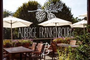 La VancelleAUBERGE FRANKENBOURG的一个带桌椅和遮阳伞的户外庭院。
