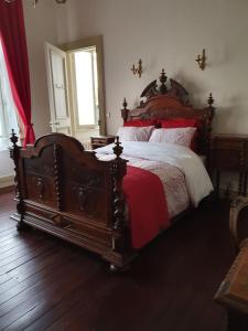 加来B & B Les Secrets des Loges的一间卧室配有一张大木床,铺有红色和白色的床单。
