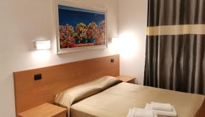 罗马日月旅馆的卧室配有一张床,墙上挂有绘画作品