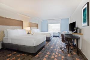 奥兰多Holiday Inn & Suites Across From Universal Orlando, an IHG Hotel的酒店客房配有两张床和一张书桌