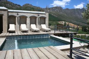 弗朗斯胡克Franschhoek Pass Villa的木制甲板上带椅子的游泳池