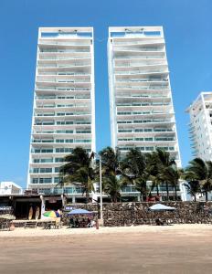 通苏帕Resort Playa Azul 3 Dormitorios的两栋高大的建筑,毗邻棕榈树海滩